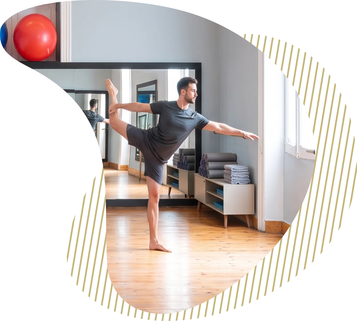 A trainer holding a standing balance pose in front of the studio mirrors